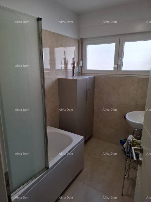 Badezimmer mit Badewanne, Duschabtrennung, Waschbecken und Fenster, hell gefliest.