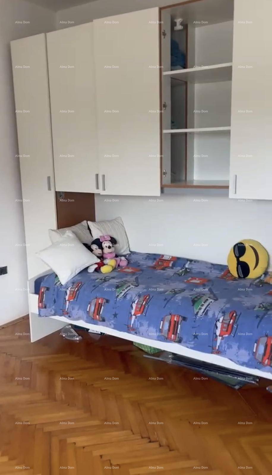 Kinderzimmer mit Einzelbett, weißen Einbauschränken und klassischem Parkettboden.