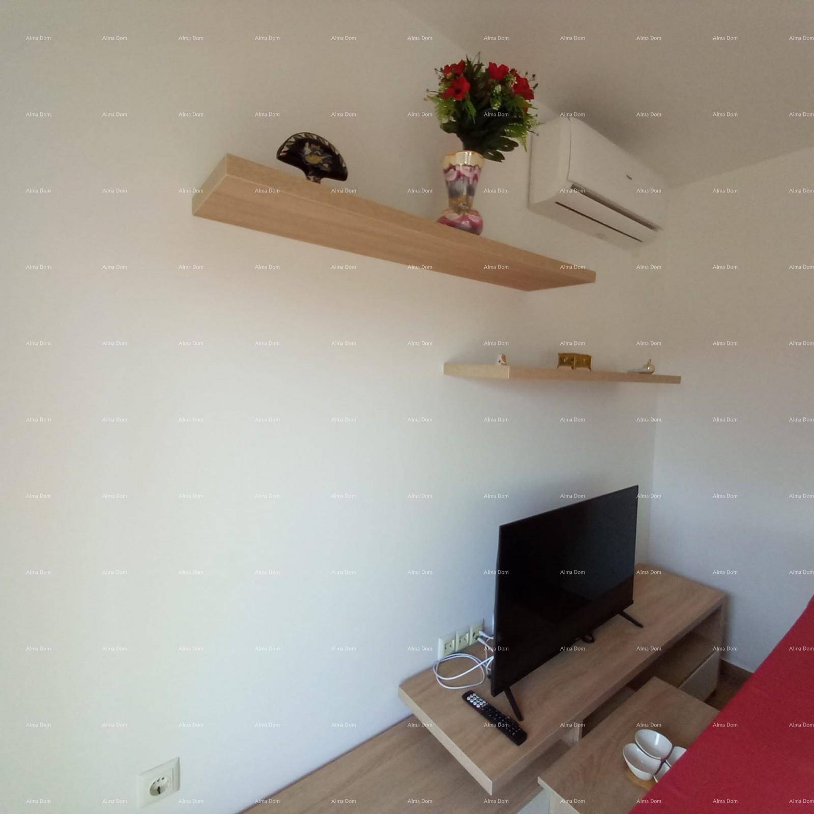 Wohnbereich mit Wandfernseher, Holzregalen und Klimaanlage für Komfort und Unterhaltung.