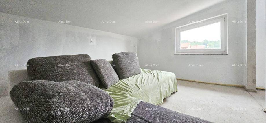 Unfertiges Wohnzimmer mit Sofa und schrägem Fenster, das auf den finalen Ausbau wartet.