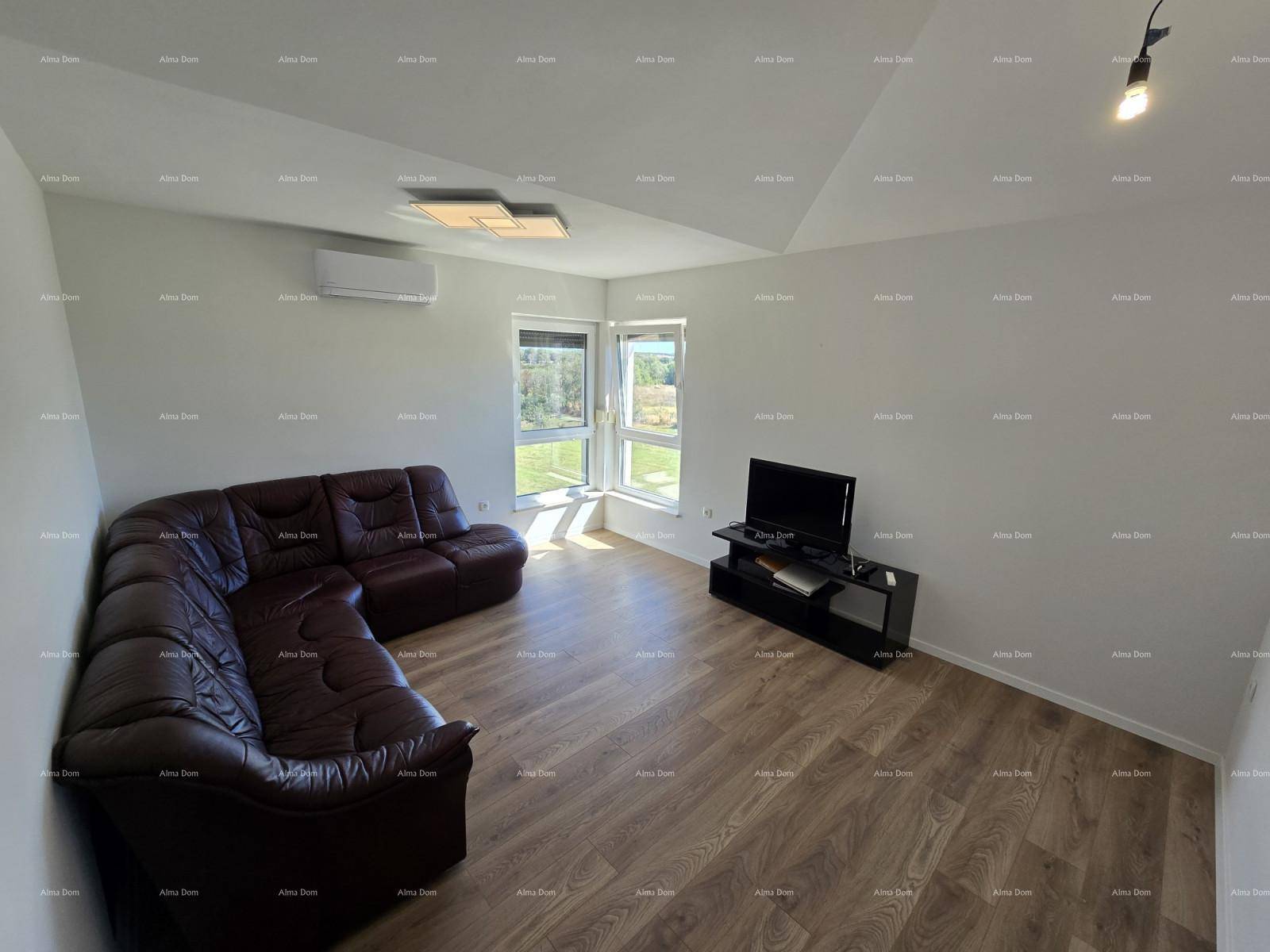 Gemütliches Wohnzimmer mit Ledersofa, TV-Möbel, Klimaanlage und großen Fenstern unter Dachschräge.