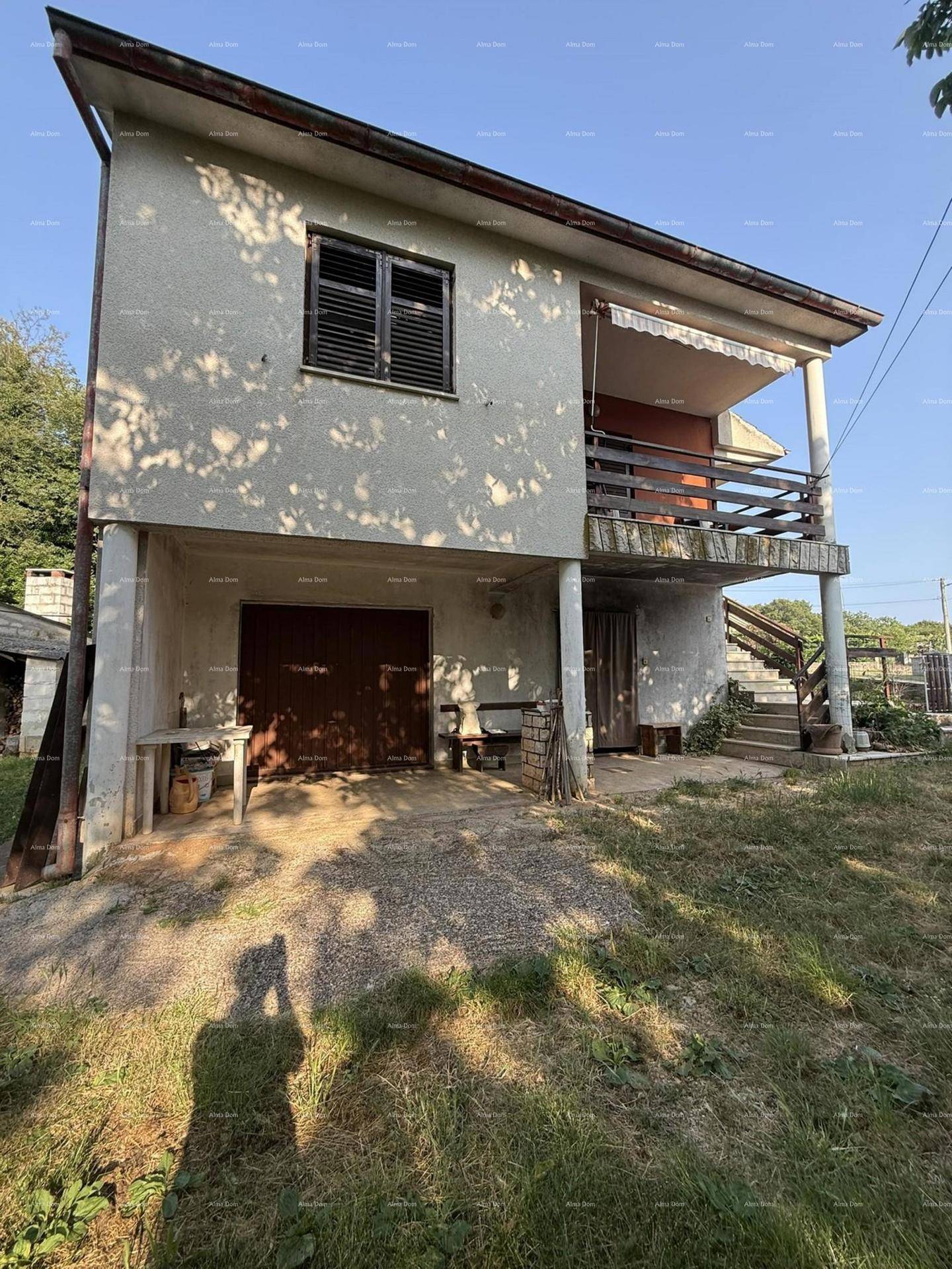 Rückansicht des Hauses mit Garage im Erdgeschoss und Balkon im Obergeschoss.