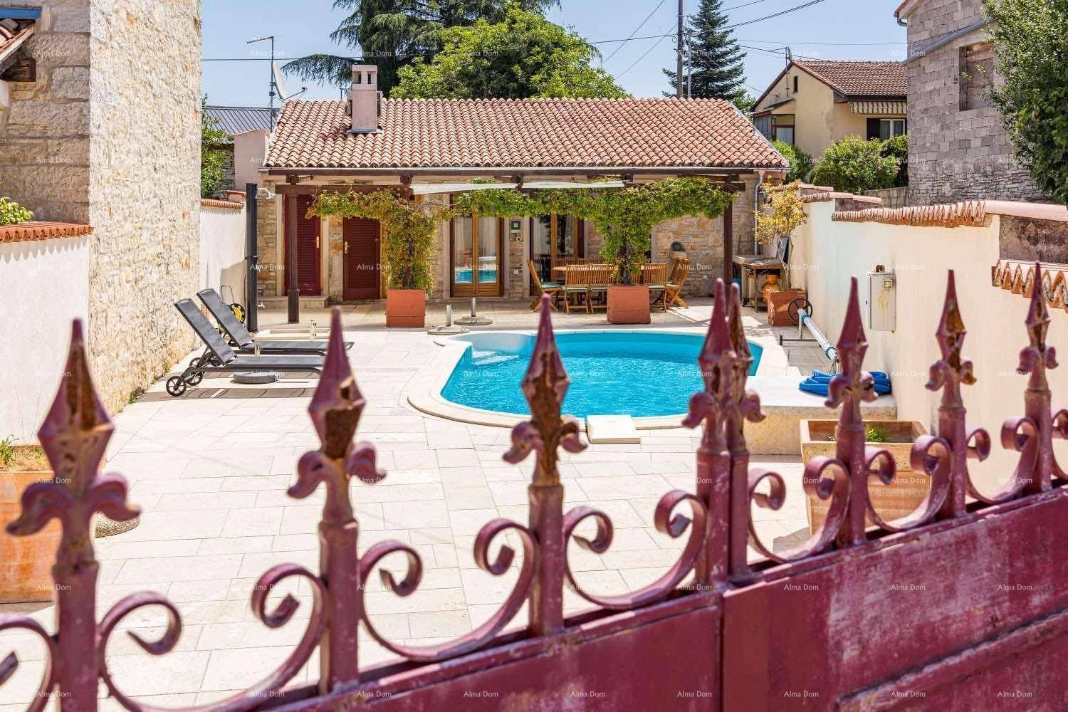 Außenbereich mit Pool, Sonnenliegen und traditionellem Gebäude im Hintergrund, durch ein Tor gesehen.