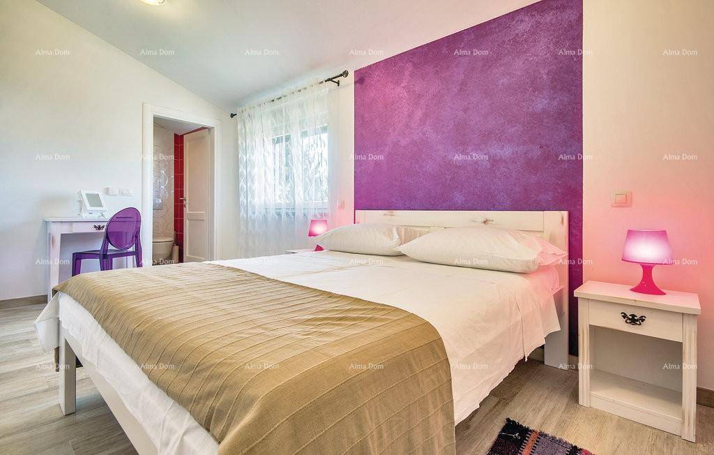 Schlafzimmer mit violetter Akzentwand, Schreibtisch und Zugang zum Badezimmer.