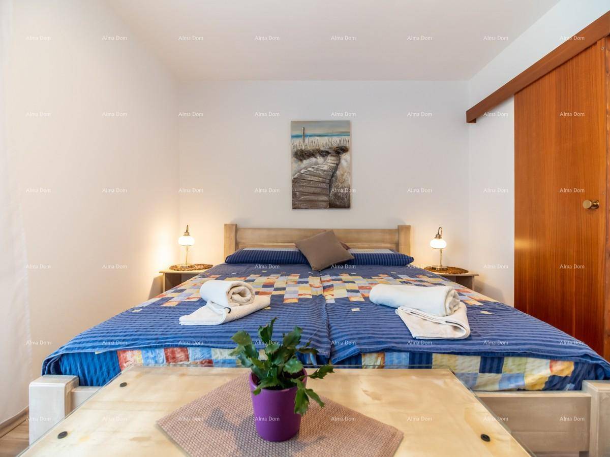 Helles Schlafzimmer mit zwei Einzelbetten, Holzboden und dekorativem Kunstwerk.