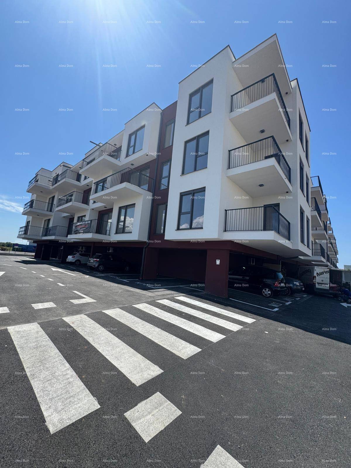 Modernes Mehrfamilienhaus mit Balkonen und Parkplätzen unter blauem Himmel.