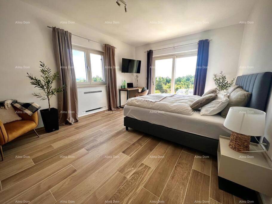 Geräumiges Schlafzimmer mit Holzboden, großen Fenstern und Blick ins Grüne.