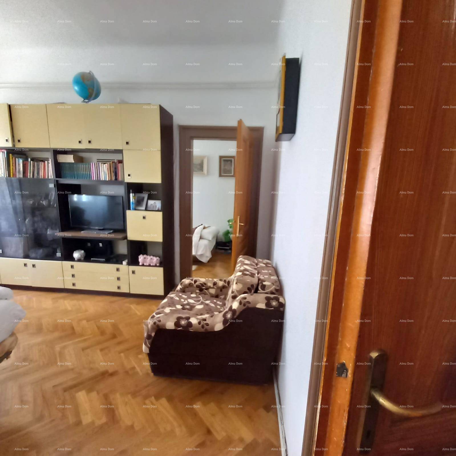 Schlafzimmer mit Holzboden und einem großen Schrank, der auch als Bücherregal dient.