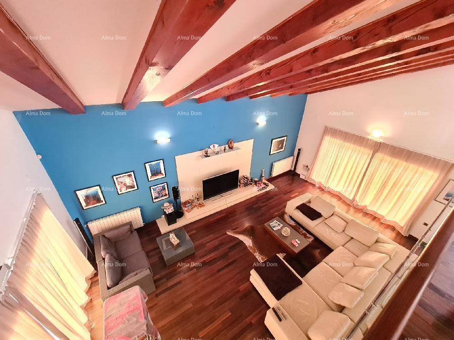 Blick von der Galerie auf das geräumige Wohnzimmer mit blauer Wand und Holzbalken.