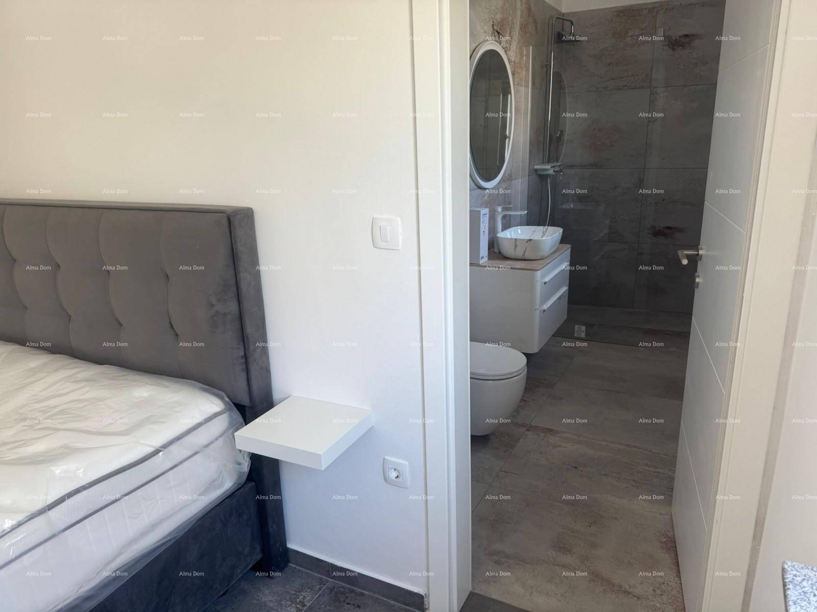 Schlafzimmer mit Bett und Blick auf das angrenzende Badezimmer mit Waschtisch und Toilette.