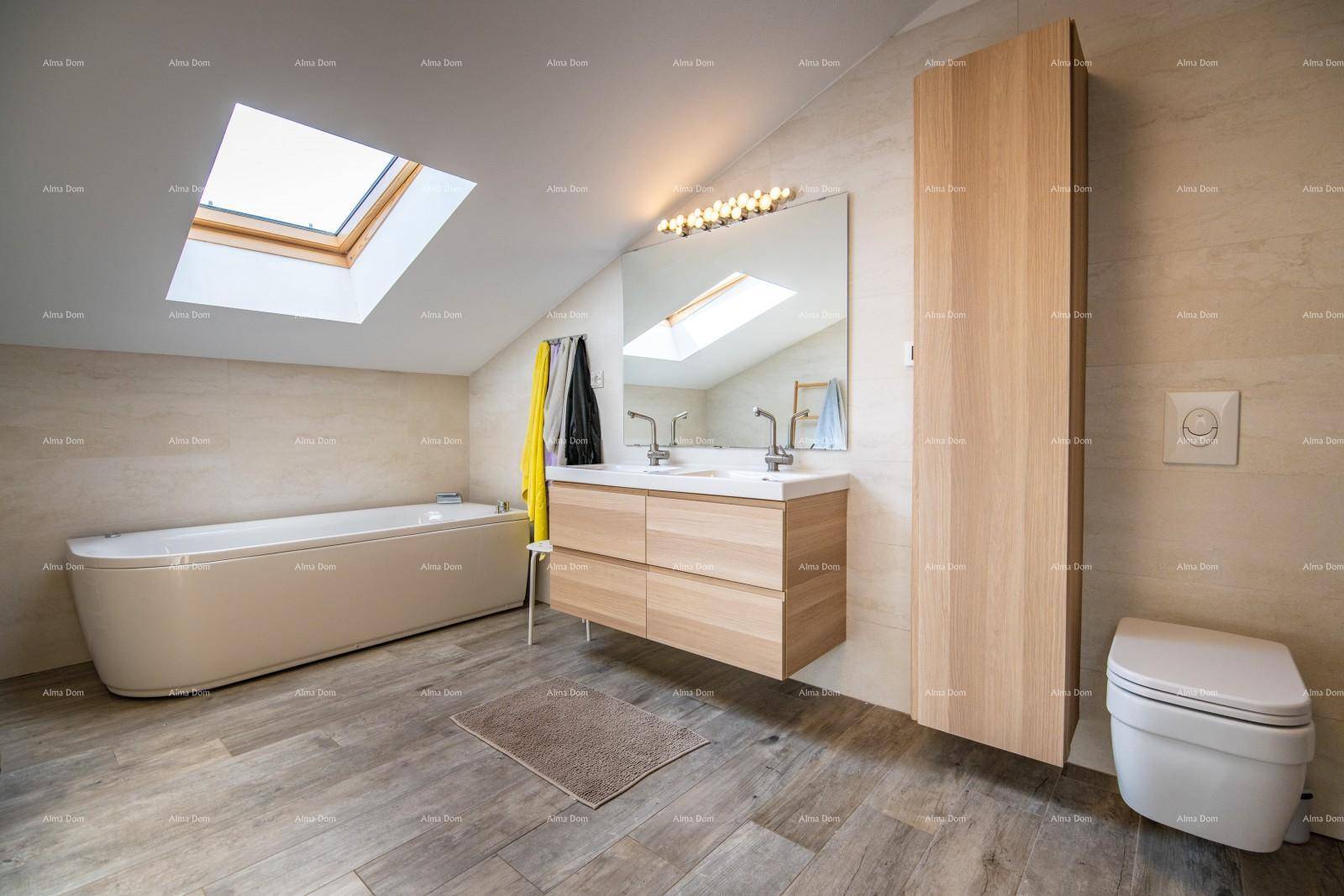 Helles Badezimmer mit Doppelwaschbecken, Badewanne, Toilette und Dachfenster.