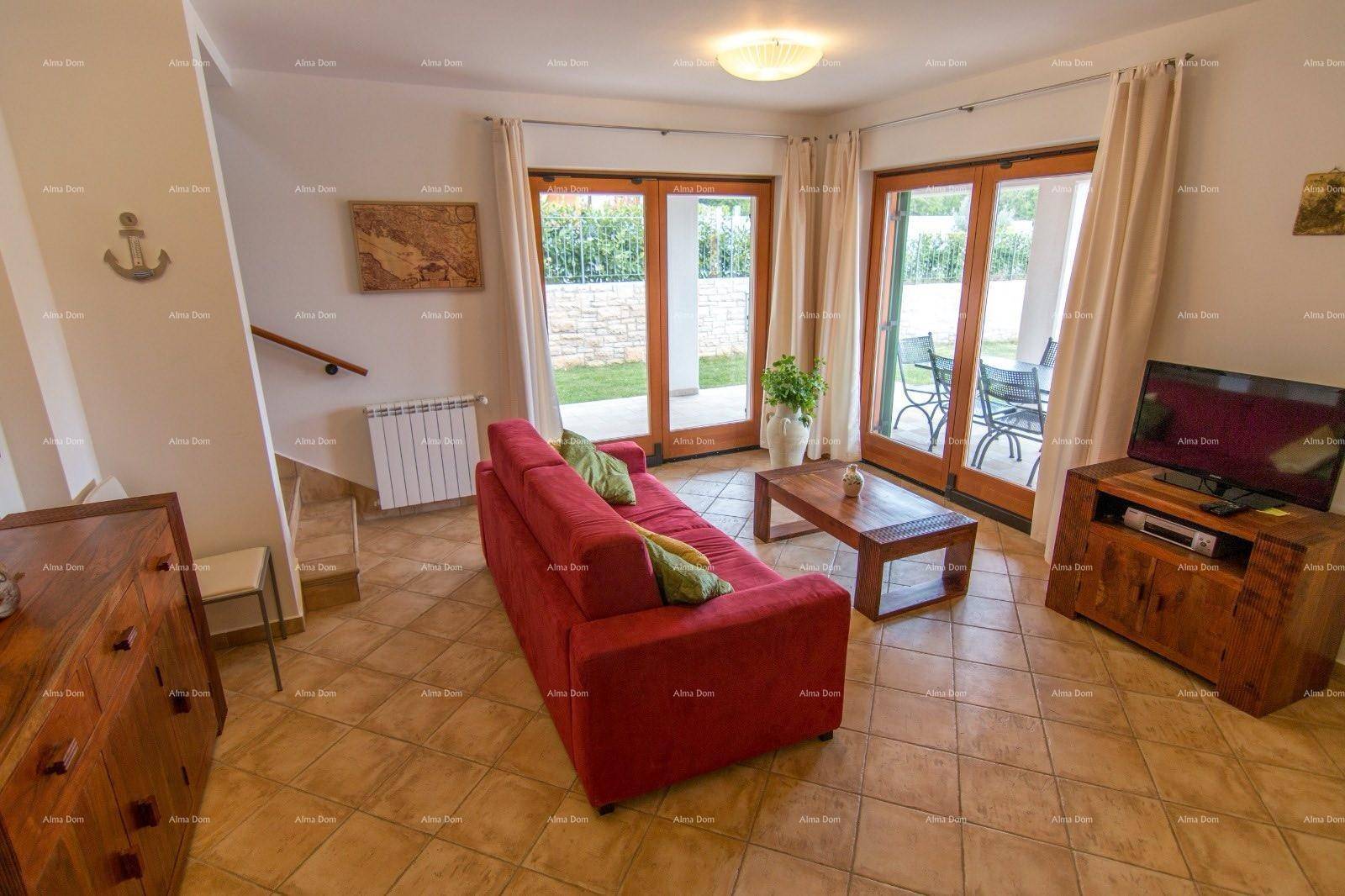 Helles Wohnzimmer mit rotem Sofa, Holztisch und Zugang zu einer Terrasse oder Gartenbereich.