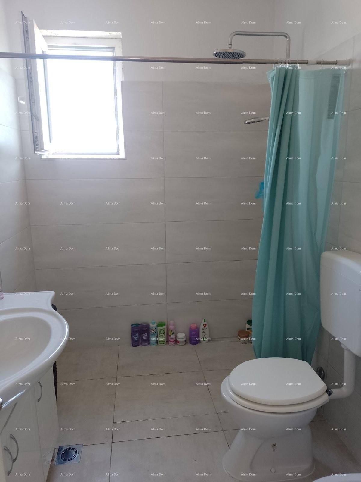 Helles Badezimmer mit Fliesen, Dusche, WC und einem Fenster für natürliche Belüftung.