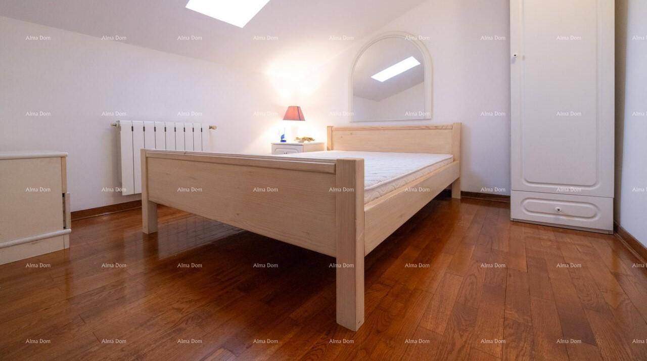 Helles Schlafzimmer im Dachgeschoss mit Holzbett, Kleiderschrank und Dachfenster.