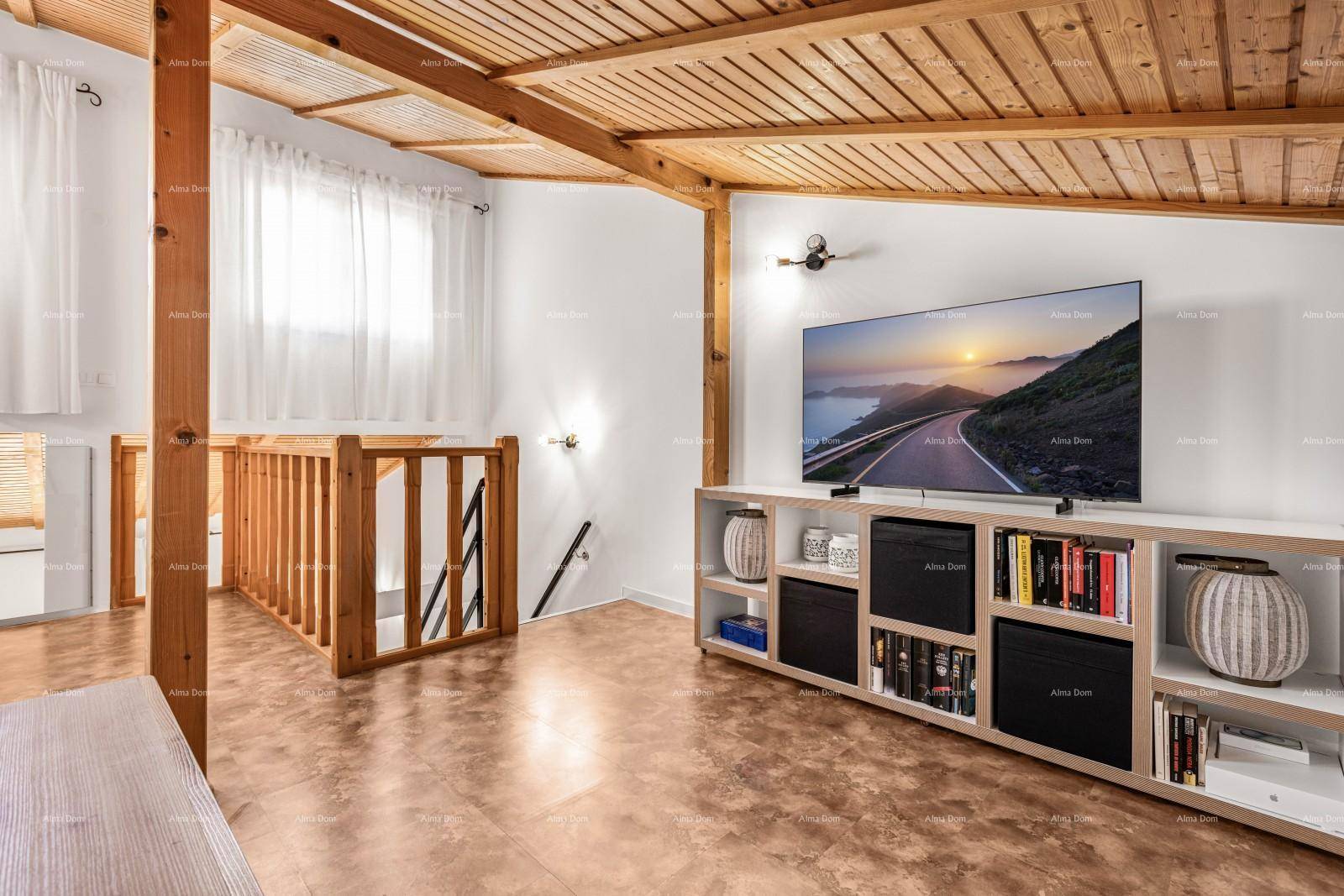 Geräumiger Dachbodenbereich mit Holzbalken, Fernseher und Blick auf die Treppe.