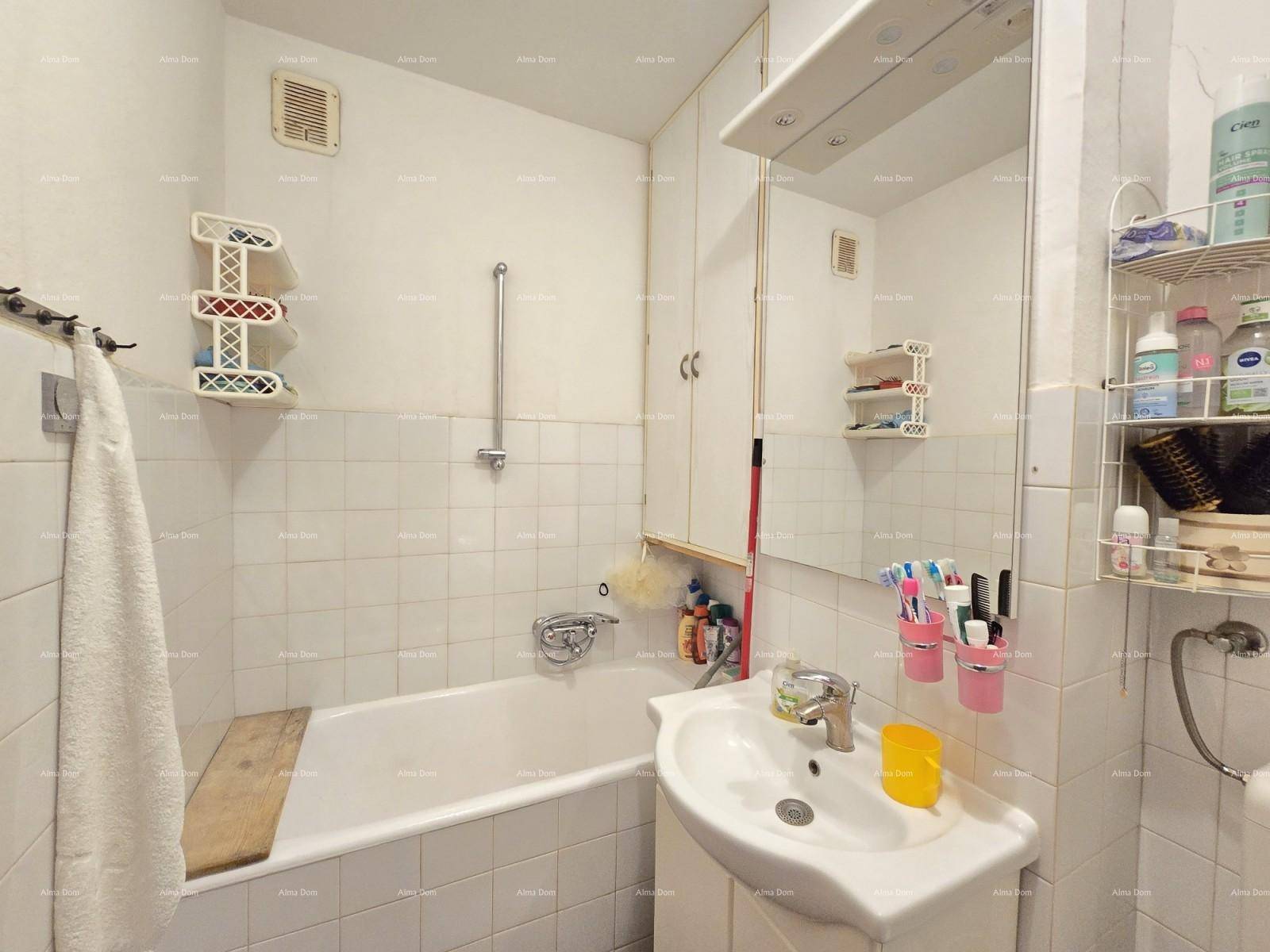 Badezimmer mit weißen Fliesen, Badewanne, Waschbecken und Spiegelschrank.