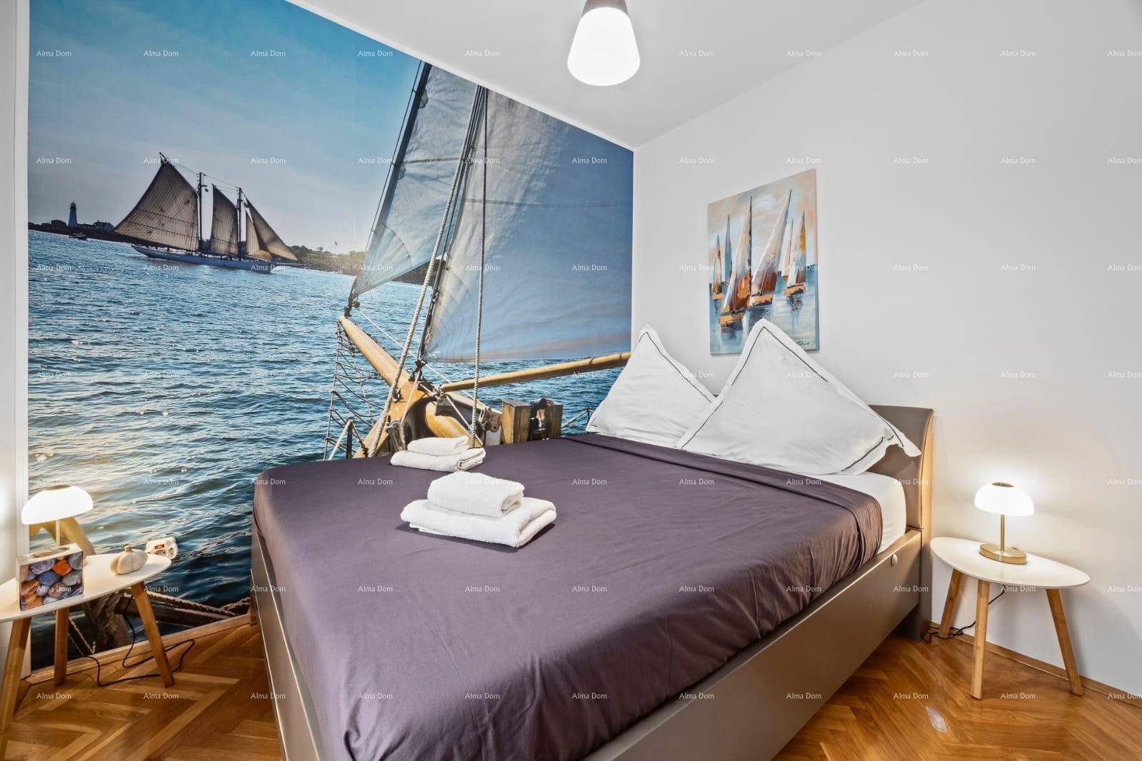 Helles Schlafzimmer mit Doppelbett, nautischem Wandbild und Holzboden, mit viel Tageslicht.