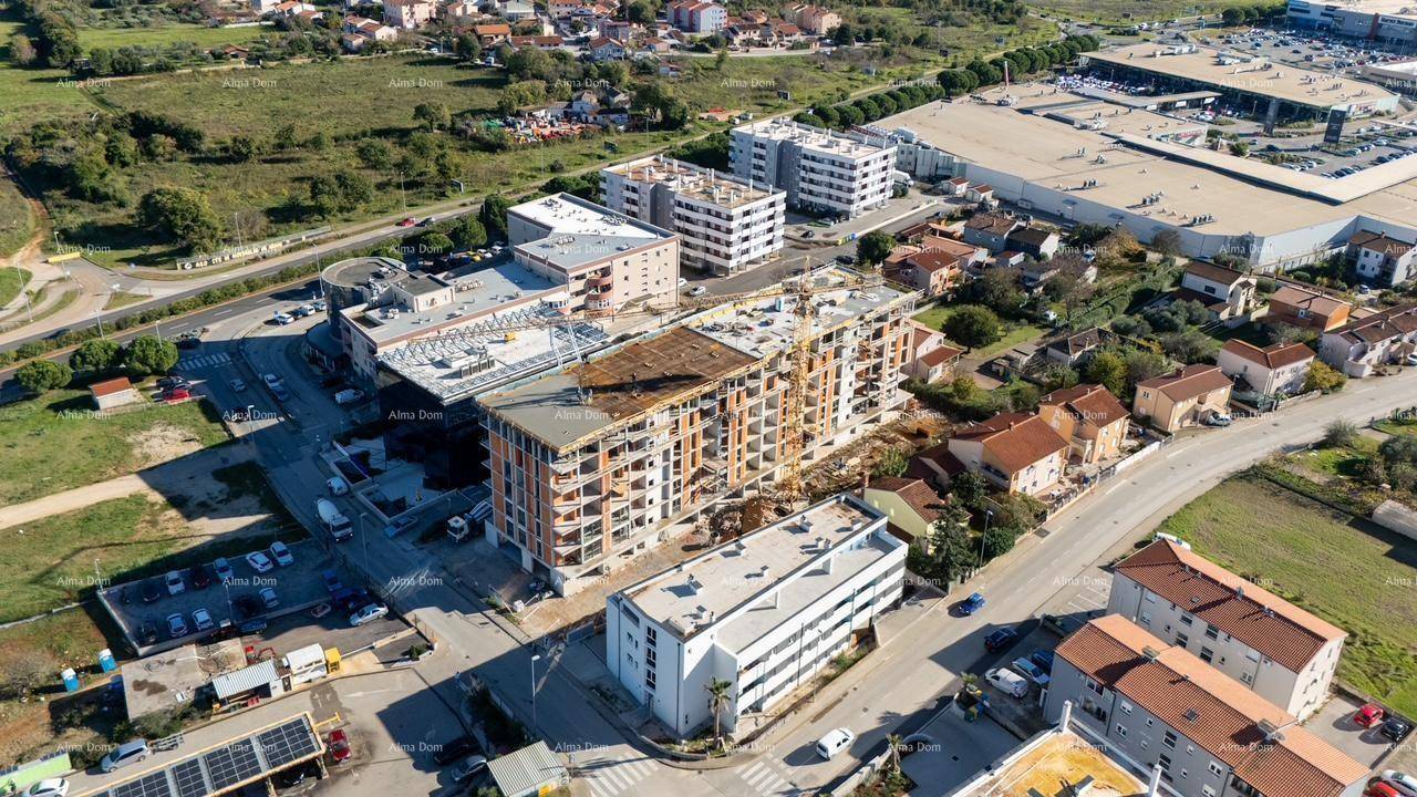 Luftaufnahme einer Baustelle in einem städtischen Umfeld mit weiteren Gebäuden.