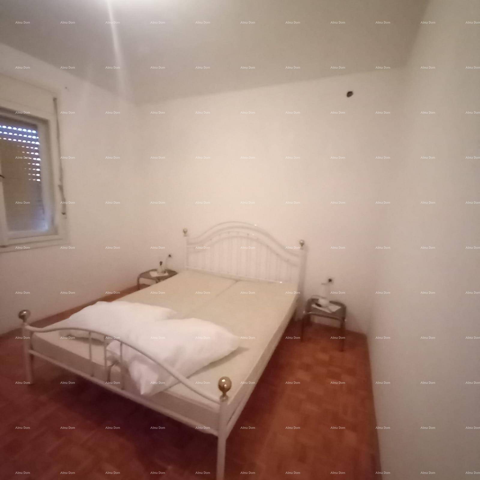 Schlafzimmer mit einem weißen Metallbett, Nachttischen und einem Fenster mit Jalousie.