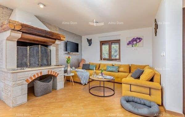 Gemütliches Wohnzimmer mit großem gelbem Sofa, Couchtisch und einem beeindruckenden Steinkamin.