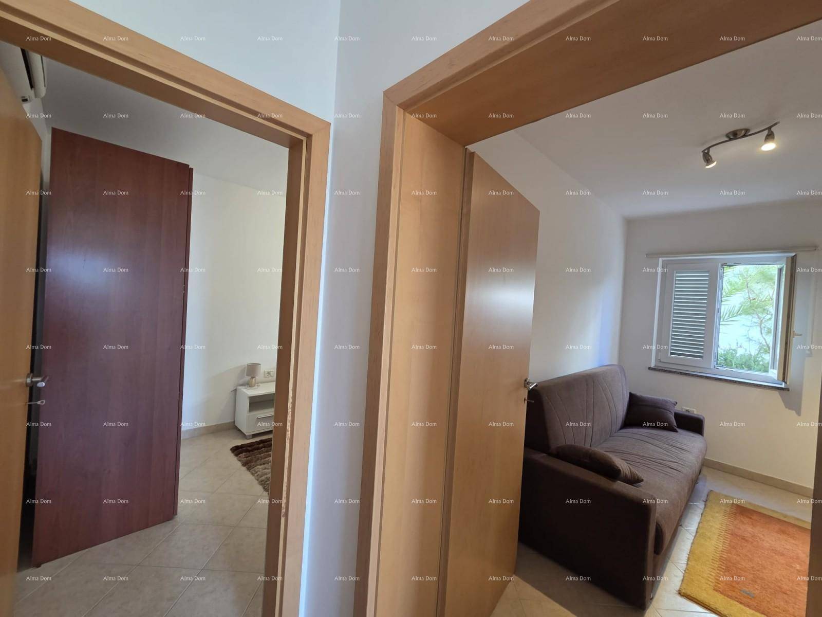 Gemütliches Wohnzimmer mit Sofa und Fenster mit Fensterläden, angrenzend an einen Flur.