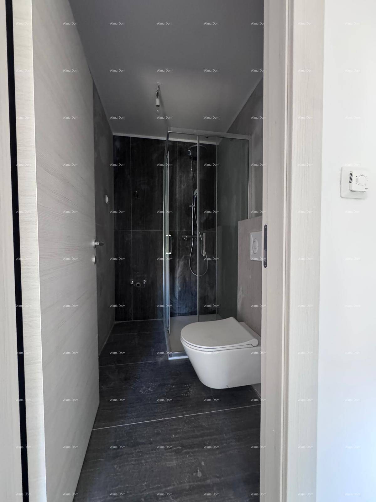 Modernes Badezimmer mit dunklen Fliesen, wandhängendem WC und einer begehbaren Dusche mit Glaswand.