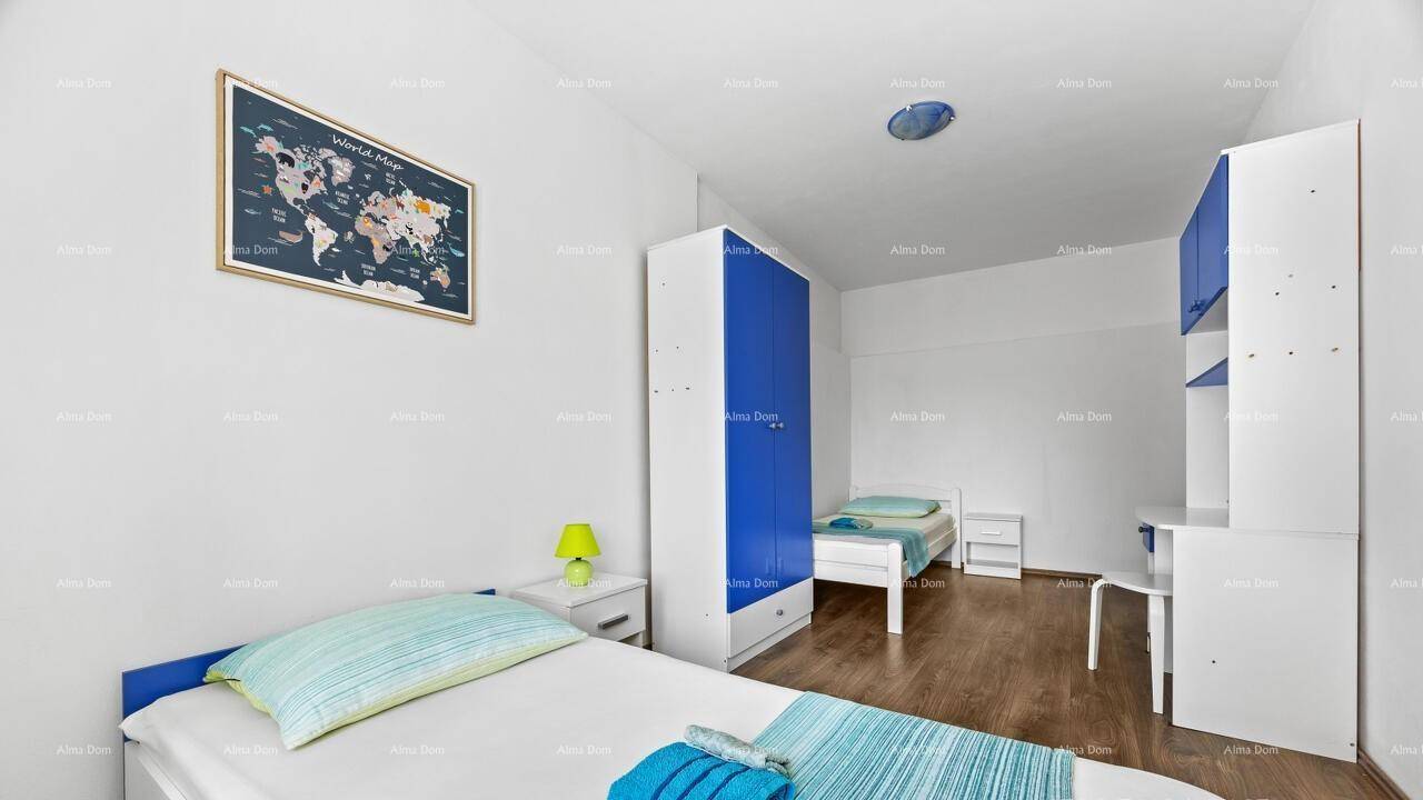 Freundliches Schlafzimmer mit zwei Einzelbetten, blauem Kleiderschrank und einer Weltkarte an der Wand.