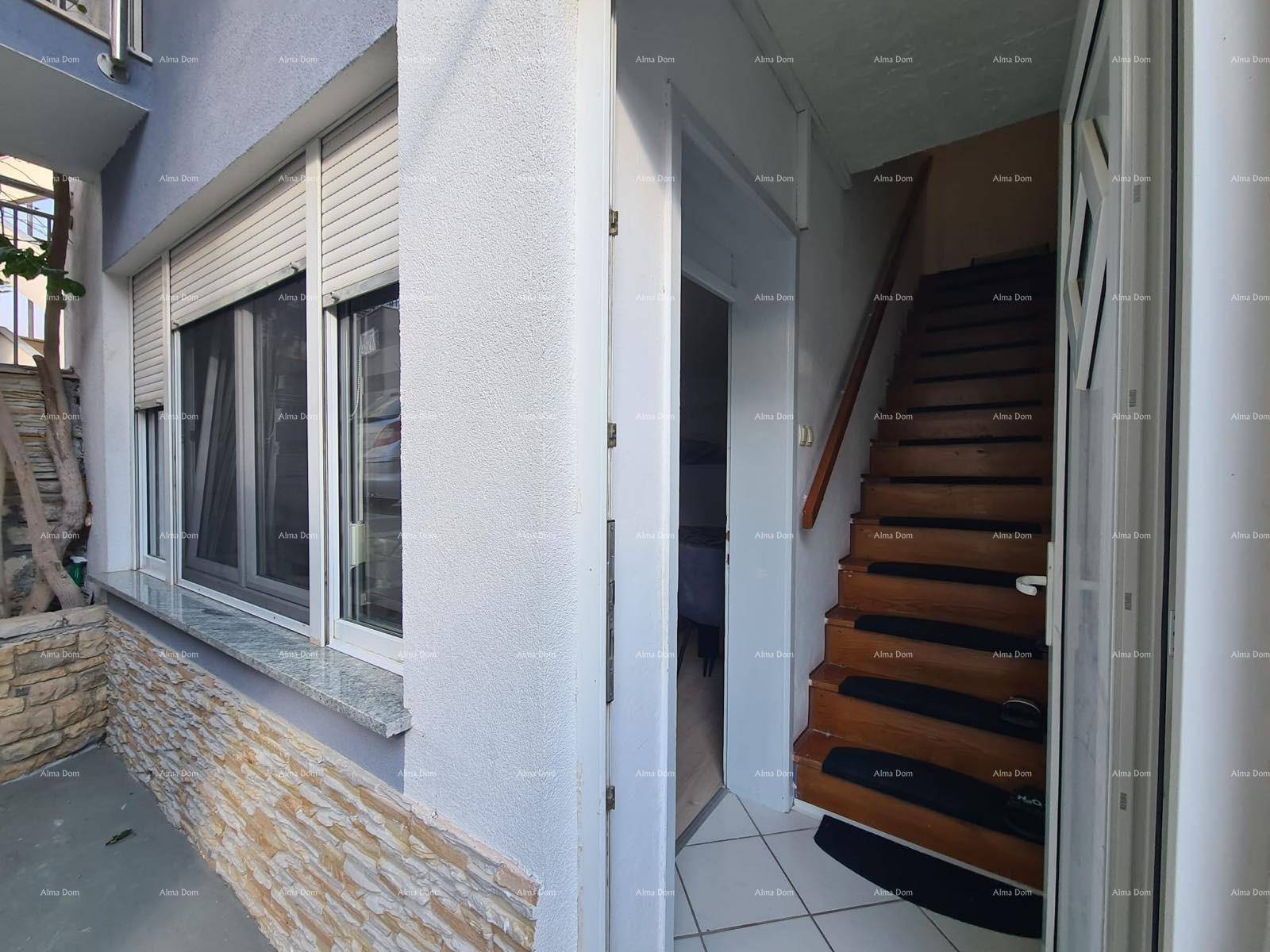 Eingangsbereich mit Fenster und Rollläden, daneben eine Holztreppe ins Innere.
