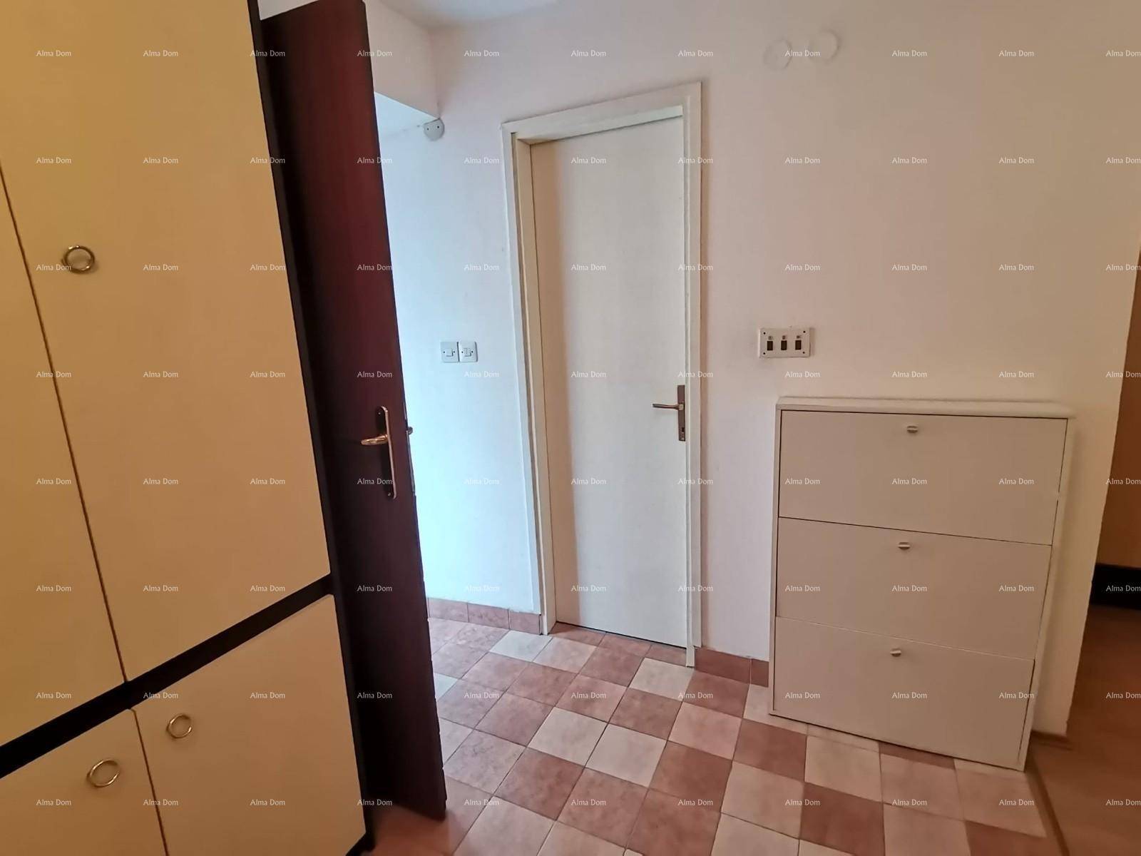 Flur mit weißer Tür, Schuhschrank und gemusterten Fliesen auf dem Boden.