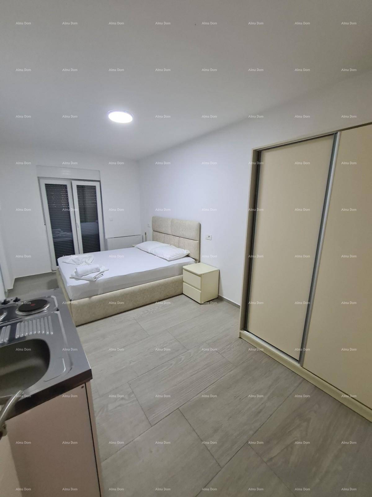 Schlafzimmer mit Doppelbett, Schiebetürenschrank und kleiner Küchenzeile, hell gefliest.