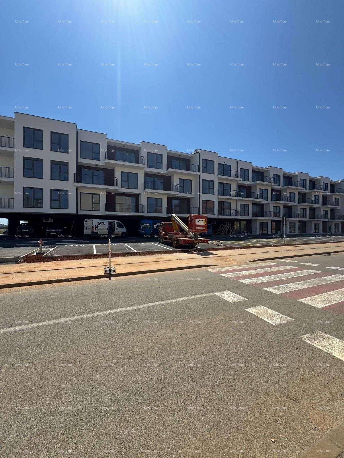 Fassade eines modernen Wohnkomplexes mit Balkonen und Parkplätzen an der Straße.