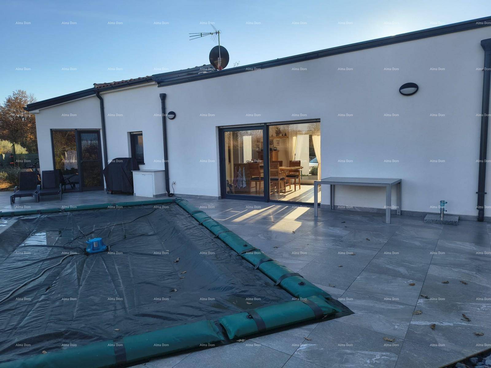 Rückseite des Hauses mit großer gefliester Terrasse und abgedecktem Poolbereich.