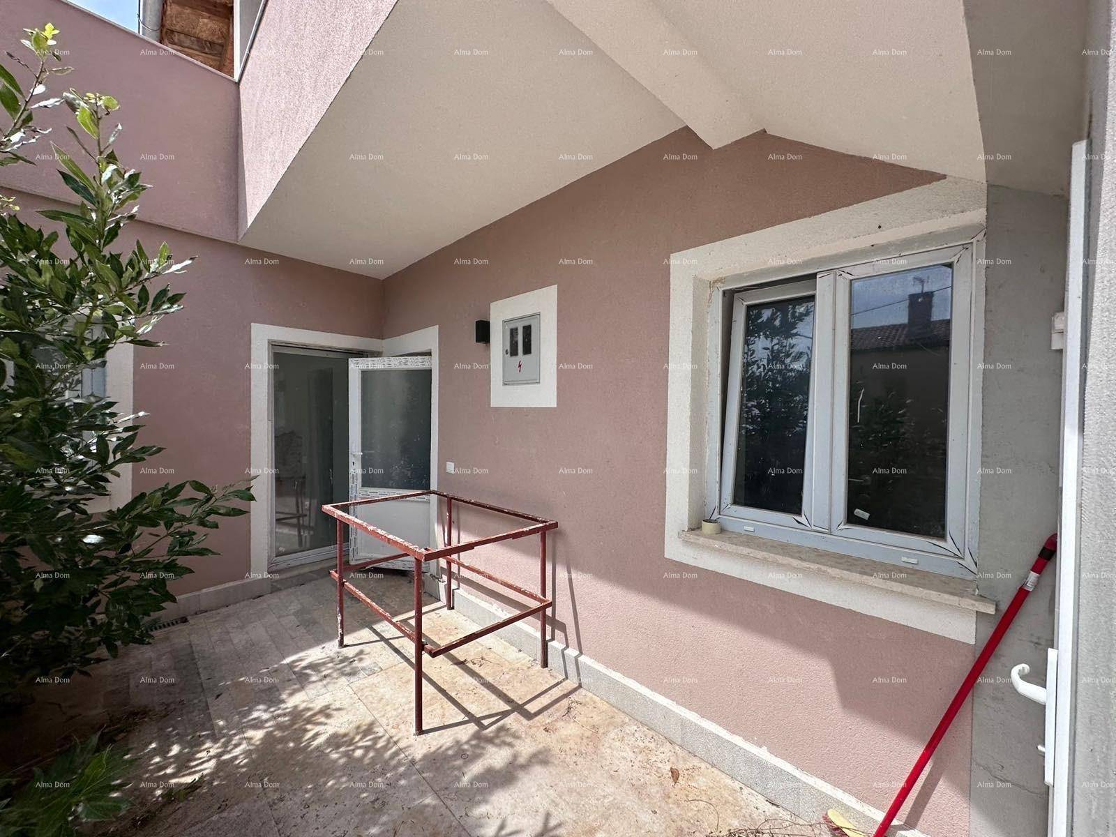 Kleiner Außenbereich neben dem Eingang mit einem Fenster und einem roten Metallgestell.