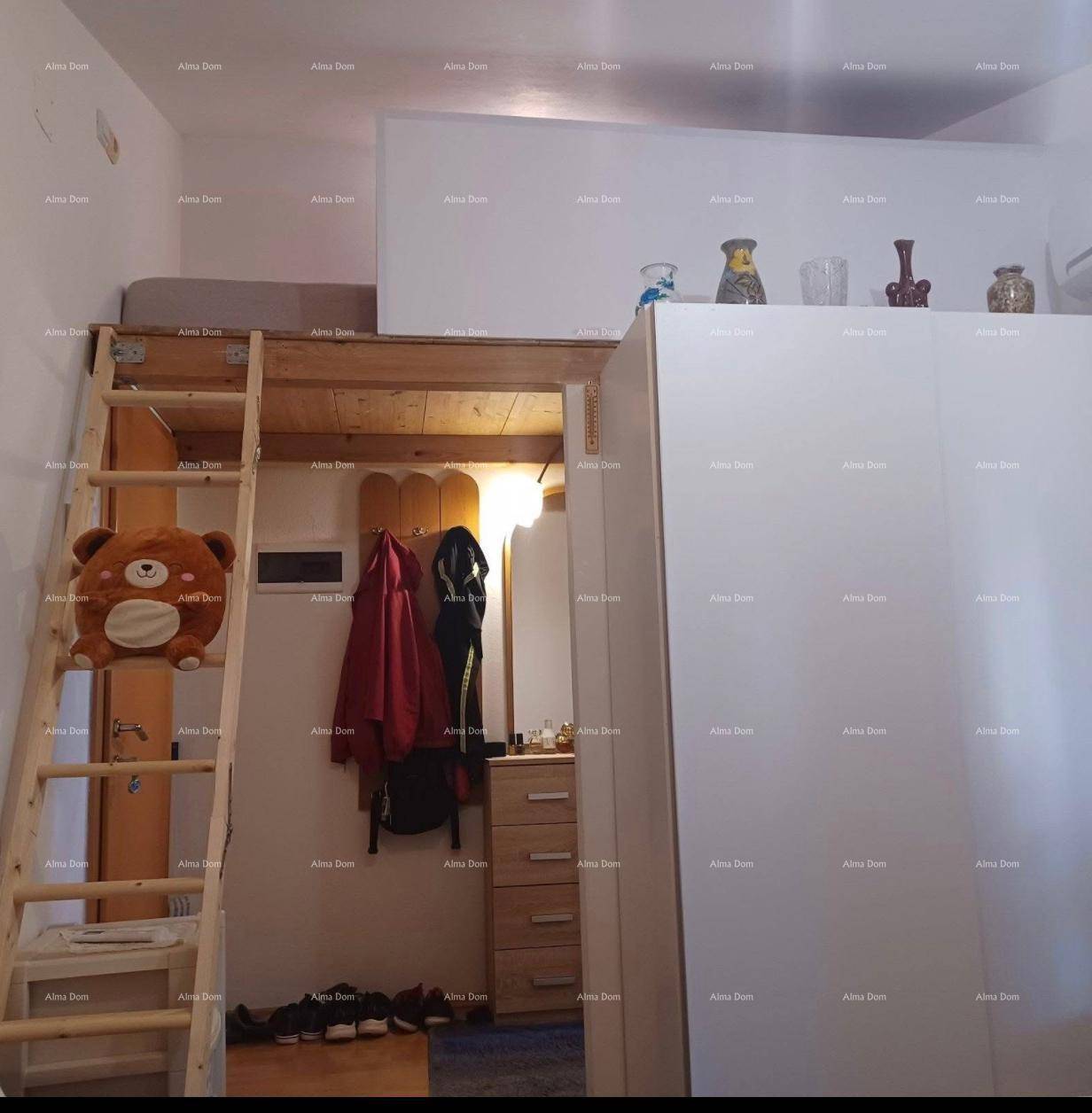 Schlafzimmerbereich mit Hochbett, Holzleiter und großem weißen Kleiderschrank für optimalen Stauraum.