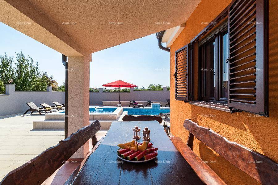Überdachte Terrasse mit rustikalem Holztisch und Blick auf den erfrischenden Poolbereich.