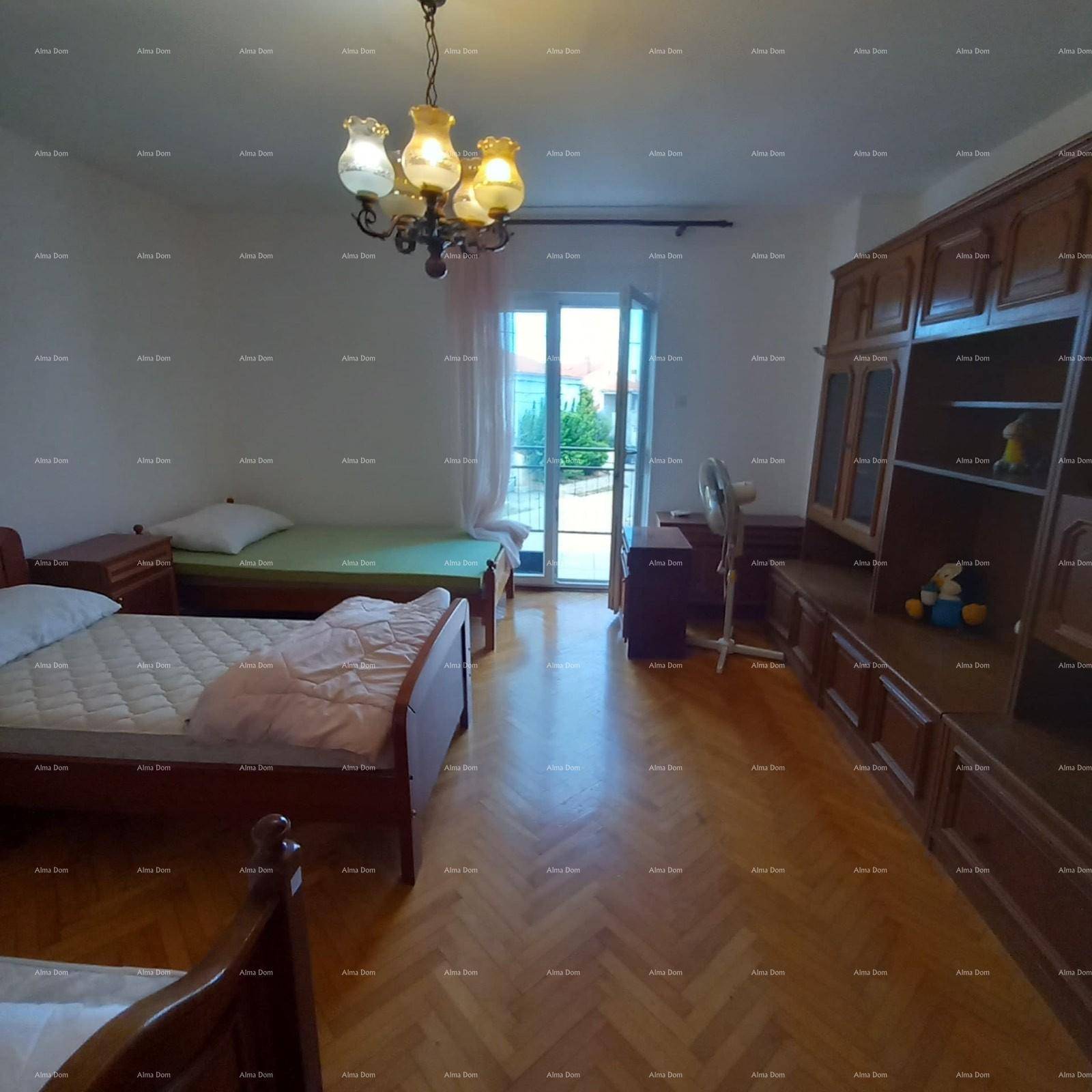 Geräumiges Schlafzimmer mit mehreren Betten, Parkettboden und Zugang zu einem Balkon.