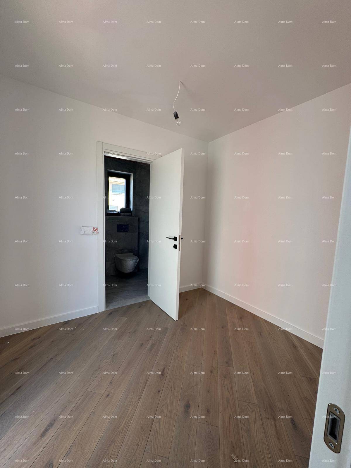 Helles Zimmer mit Holzboden und Zugang zu einem modernen Badezimmer.