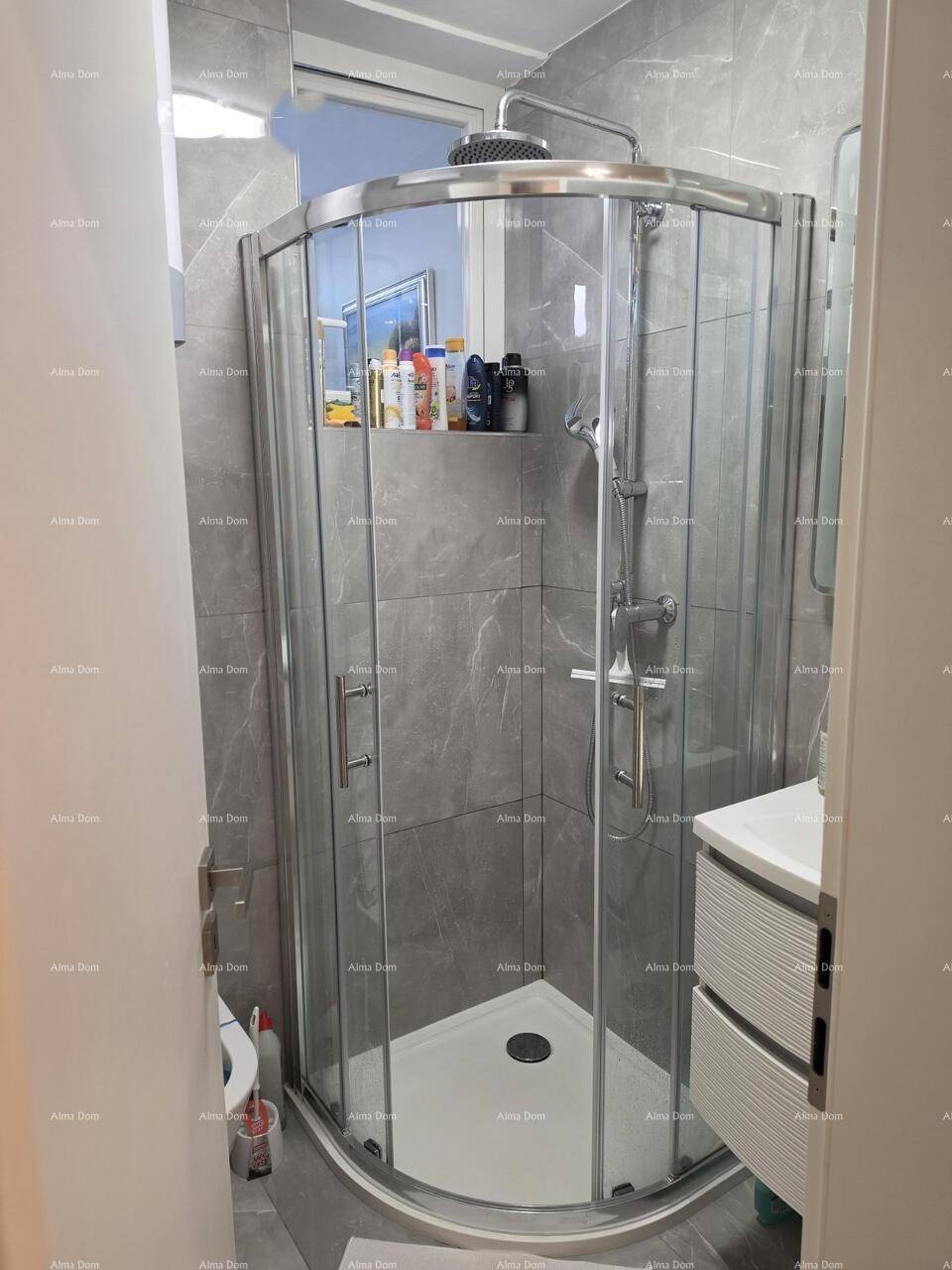 Moderne Duschkabine mit Glaswänden und Regenduschkopf in einem gefliesten Badezimmer.
