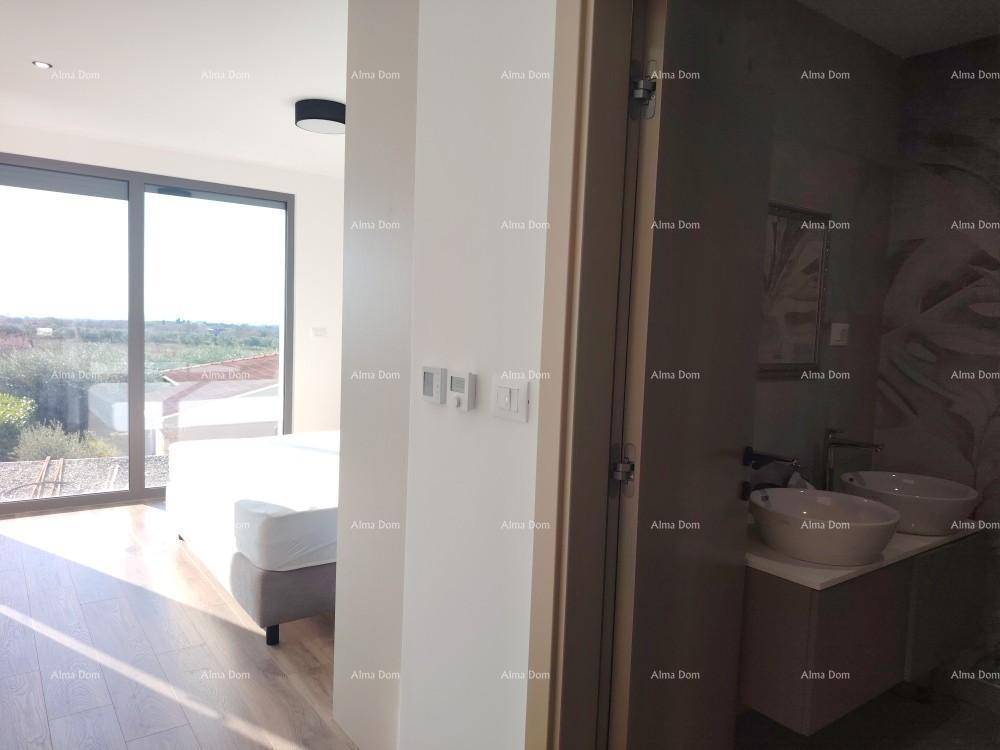 Flur mit Blick in ein helles Schlafzimmer und ein Badezimmer mit Doppelwaschbecken.