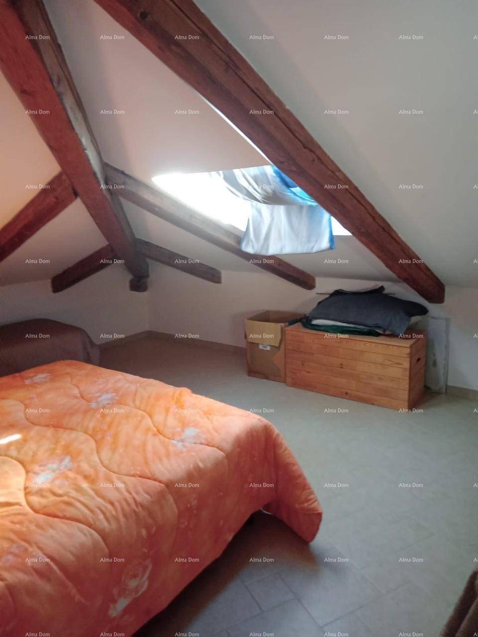Dachgeschoss-Schlafzimmer mit sichtbaren Holzbalken, Dachschräge und viel Tageslicht.