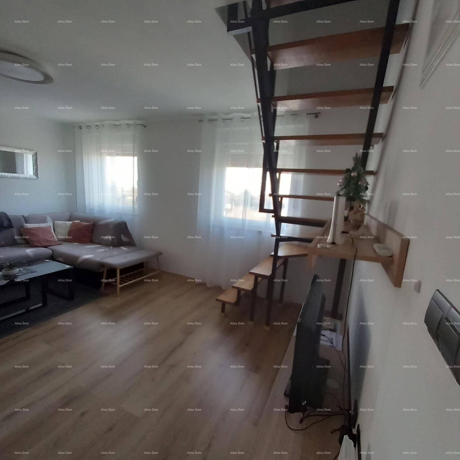 Helles Wohnzimmer mit Sofa, Fenstern und offener Holztreppe.