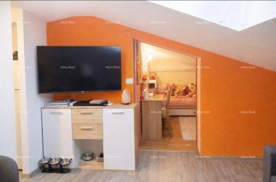 Wohnbereich mit Fernseher und Schrank, der zu einem weiteren Zimmer im Dachgeschoss führt.