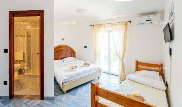 Helles Schlafzimmer mit Doppelbett und Einzelbett, direktem Zugang zu einem Badezimmer.
