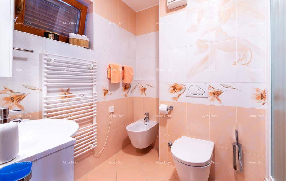 Badezimmer mit WC, Bidet, Waschbecken und beheiztem Handtuchhalter, dekoriert mit floralen Fliesen.