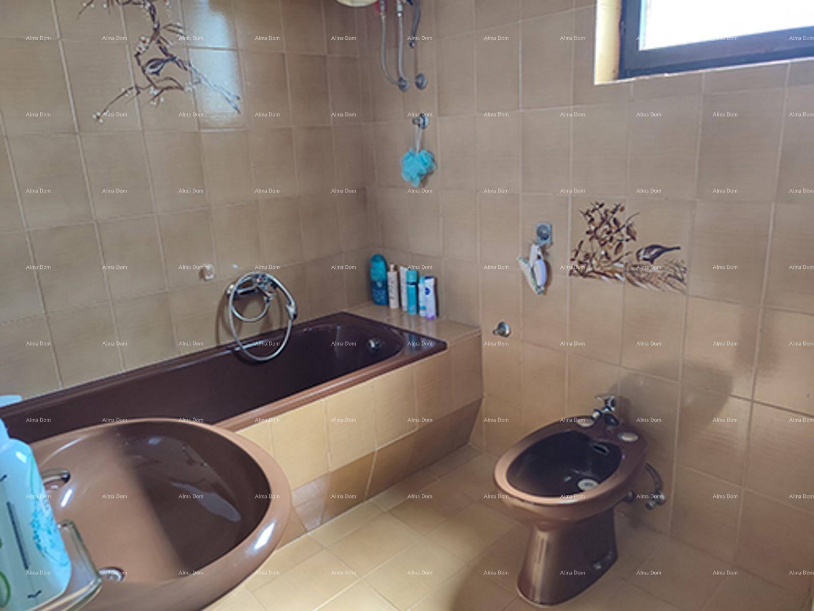 Badezimmer im Stil der 80er Jahre mit braunen Fliesen, Badewanne, Bidet und Fenster.