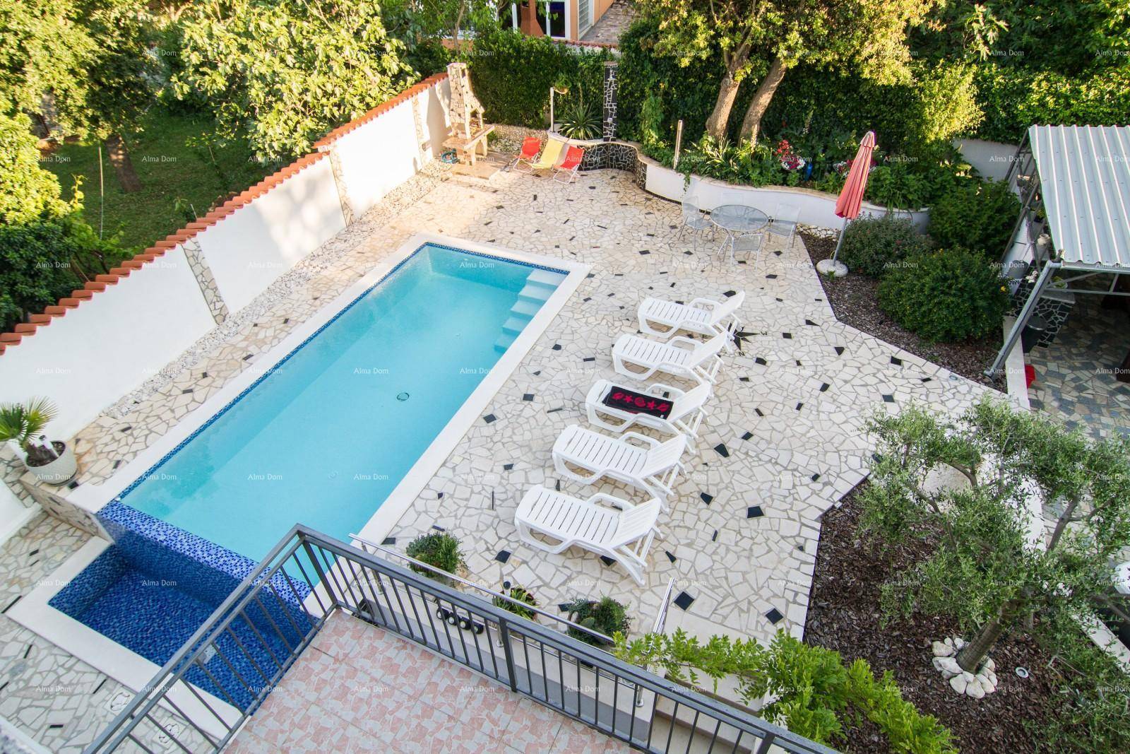 Vogelperspektive des Pools und des gepflasterten Außenbereichs mit Sonnenliegen und Garten.