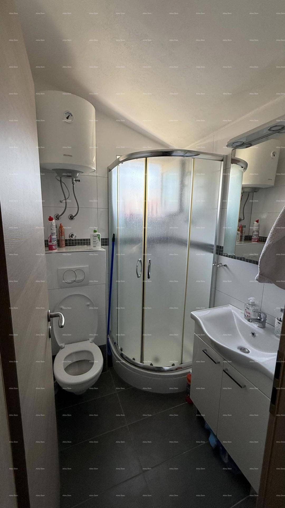 Badezimmer mit Toilette, Waschbecken und einer Eckduschkabine, ausgestattet mit einem Warmwasserboiler.