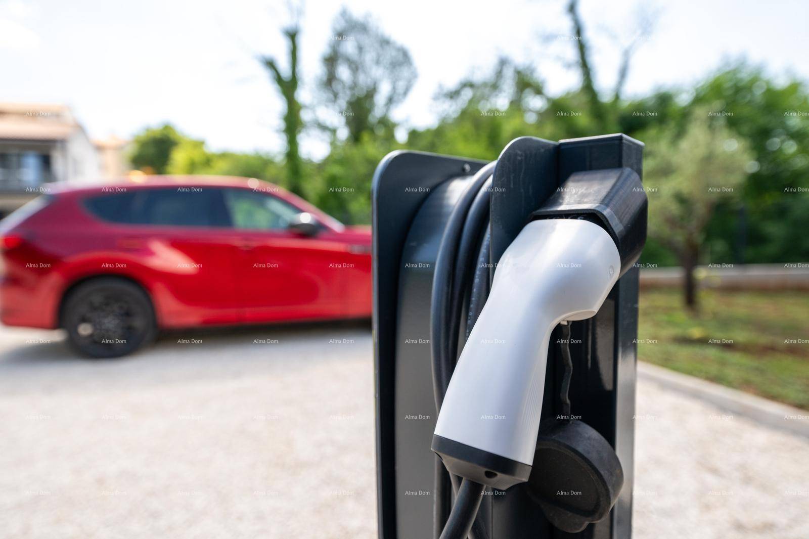 Ladestation für Elektrofahrzeuge auf dem Grundstück mit einem roten Auto im Hintergrund.