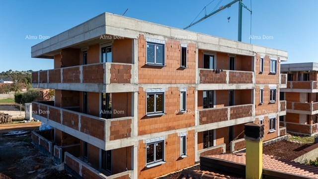Gebäude im Rohbau mit bereits installierten Fenstern und Balkonstrukturen, ein Baukran im Hintergrund.