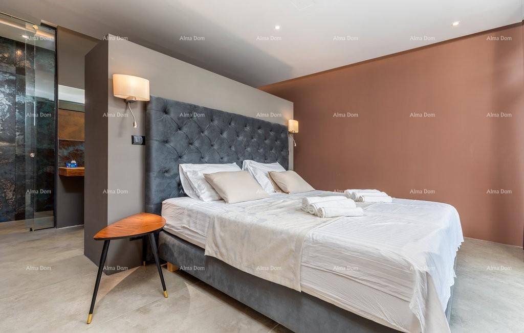 Stilvolles Schlafzimmer mit grauem Polsterbett und integriertem Badezimmerbereich, hell und modern gestaltet.